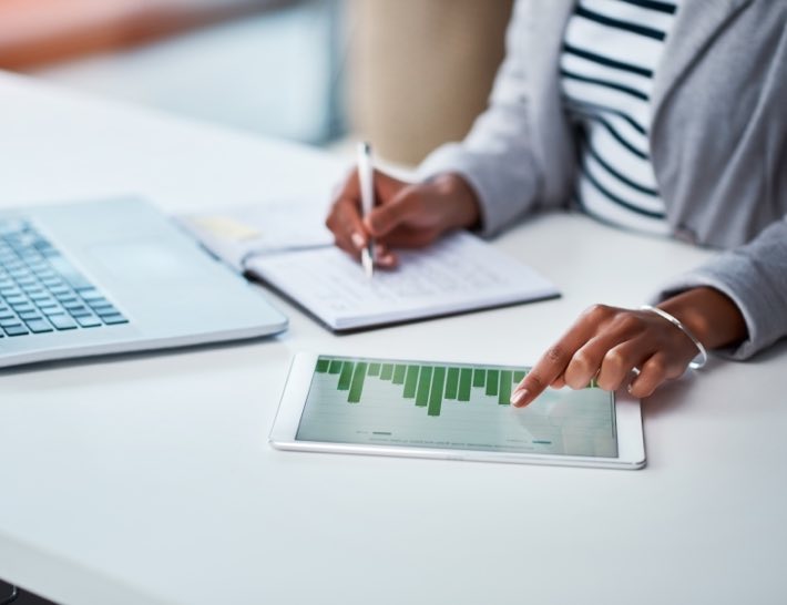 woman pointing to bar graph on tablet taking notes for utility expense management