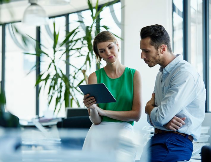 man inquisitively looking at tablet held by woman